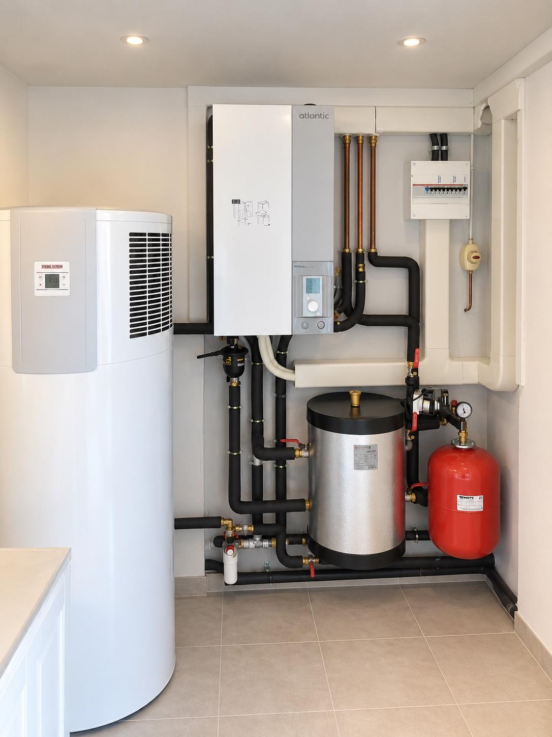 Module intérieur de pompe à chaleur air/eau installé par Priorité Environnement : unité murale, ballon d'eau chaude, bouteille de découplage, vase d'expansion et tableau électrique, tuyauterie calorifugée